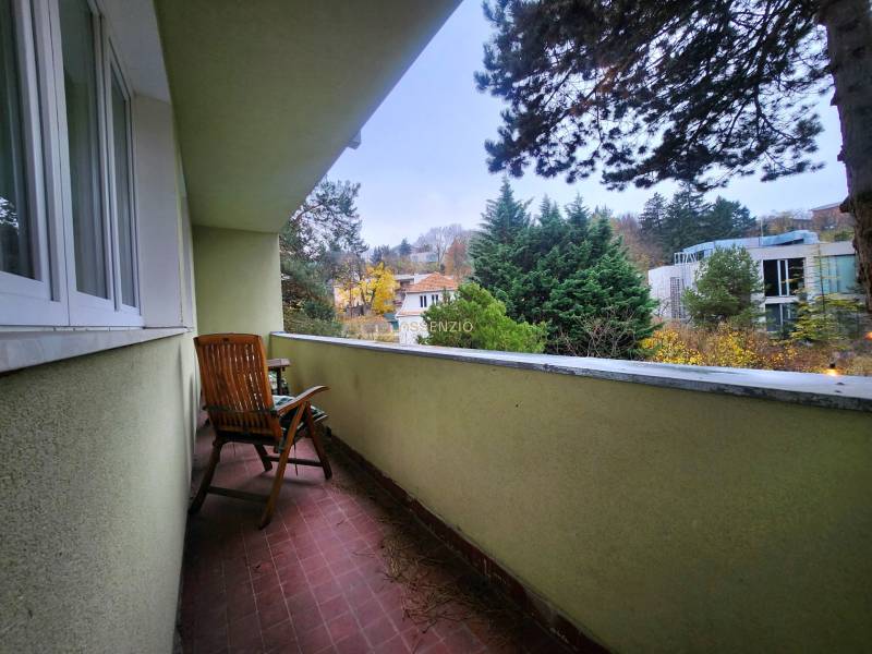 A balcony with a view of greenery and buildings, part of a 2-room apartment.