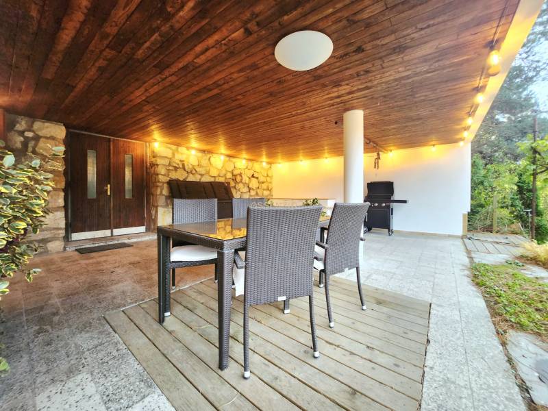Covered terrace with a stone wall, rattan furniture, and lighting, ideal for relaxation.