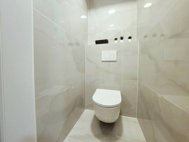 Bathroom with toilet in a 2-room apartment, tiled with light ceramic tiles.