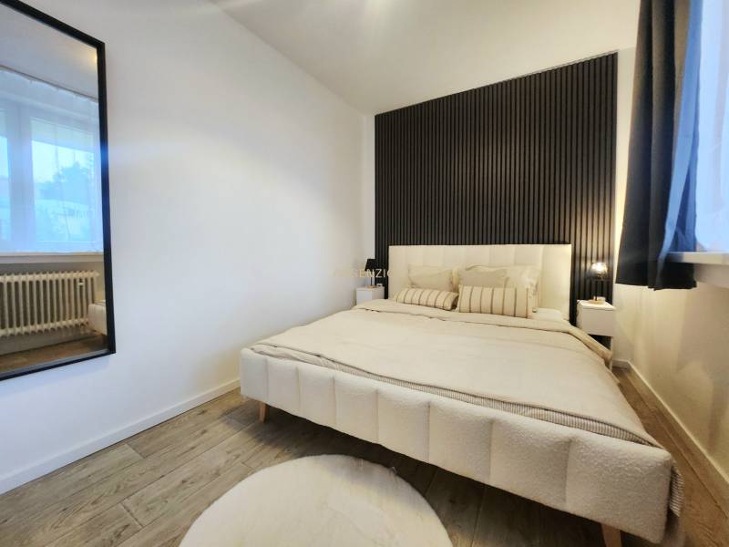 Bedroom in a 2-room apartment with a crib, dark wall, and floor with wood decor.