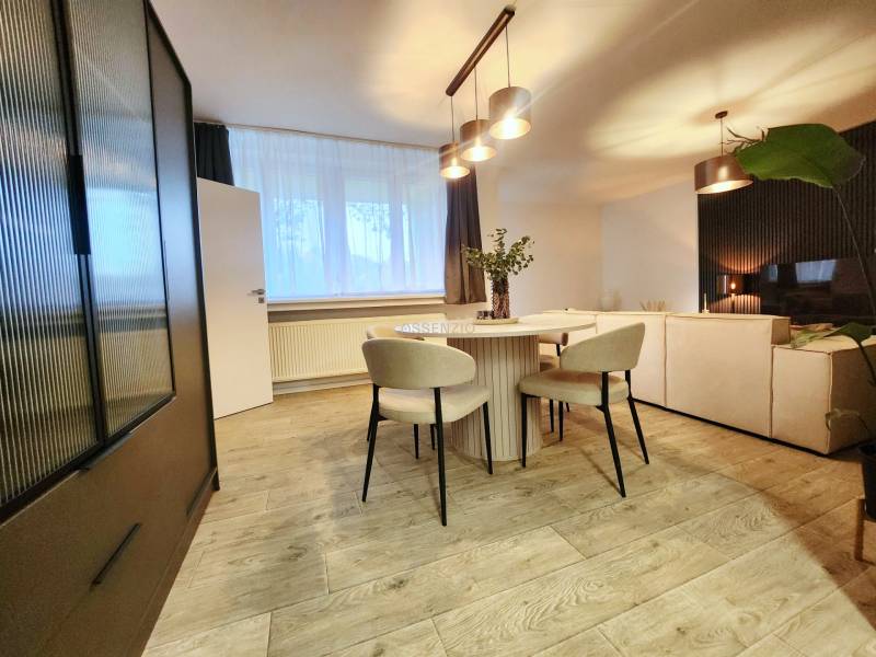 Dining area with a round table, chairs, and a wooden decor floor in a 2-room apartment.