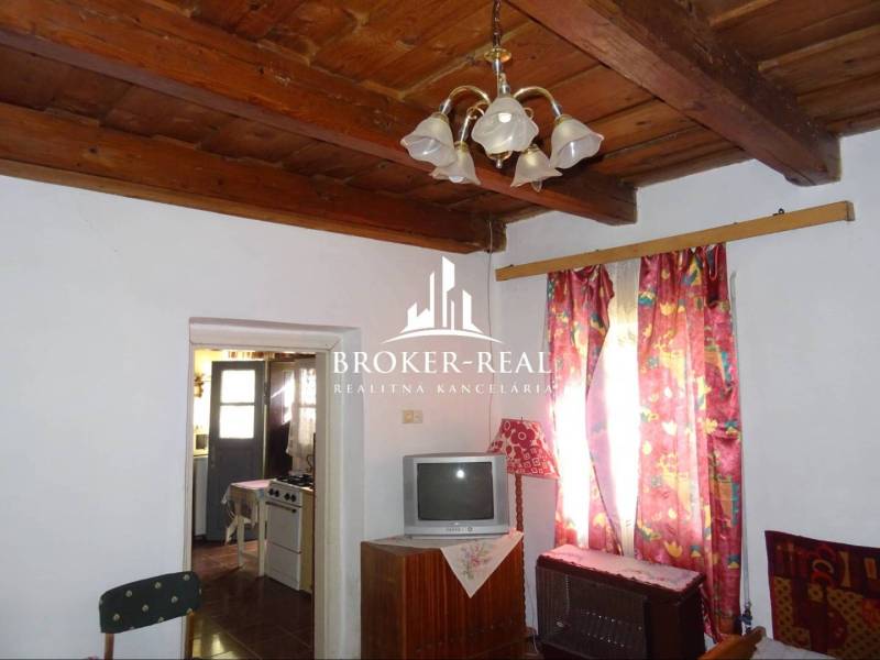 Living room in a family house with a wooden ceiling, curtains, and a television.