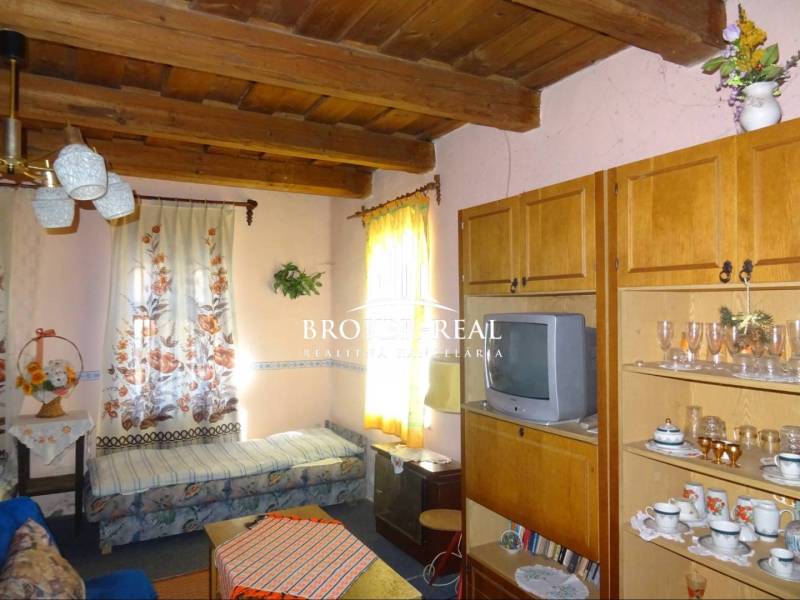 Living room in a family house with a wooden beam ceiling, furniture, and a television.