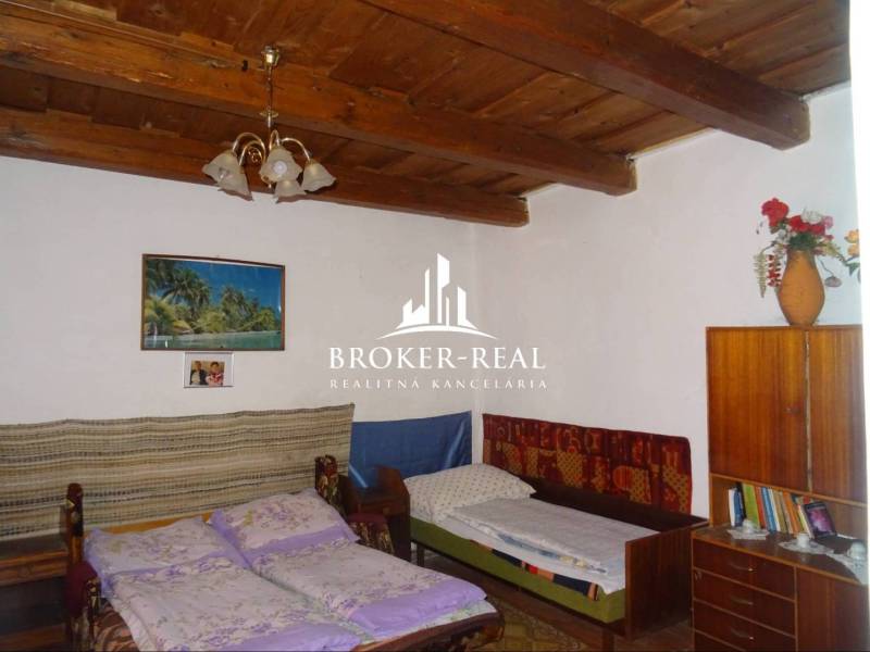 Bedroom in a family house with a wooden ceiling, beds, and a cabinet.