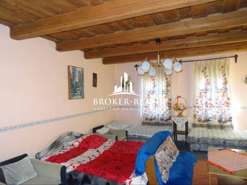 A room in a family house with a wooden ceiling, sofas, and colorful curtains.