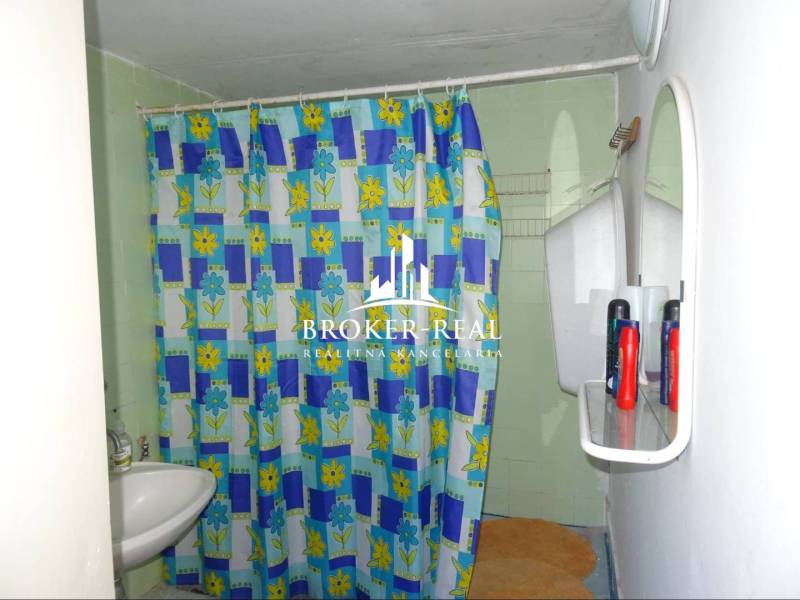A bathroom in a family house with a colorful shower curtain and a mirror.