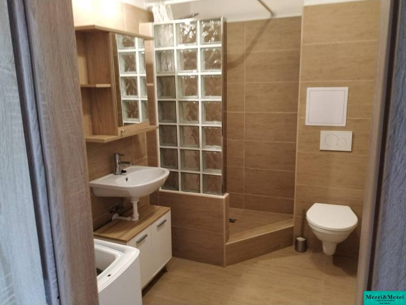 Bathroom with tiles, shower cabin, and sink in a studio apartment.