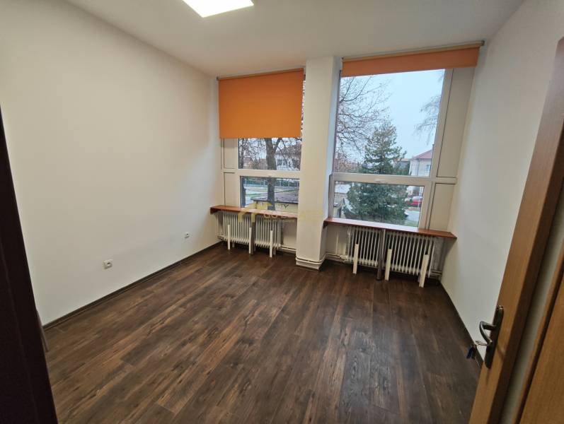 Offices with orange blinds, wood-patterned flooring, and radiators under large windows.