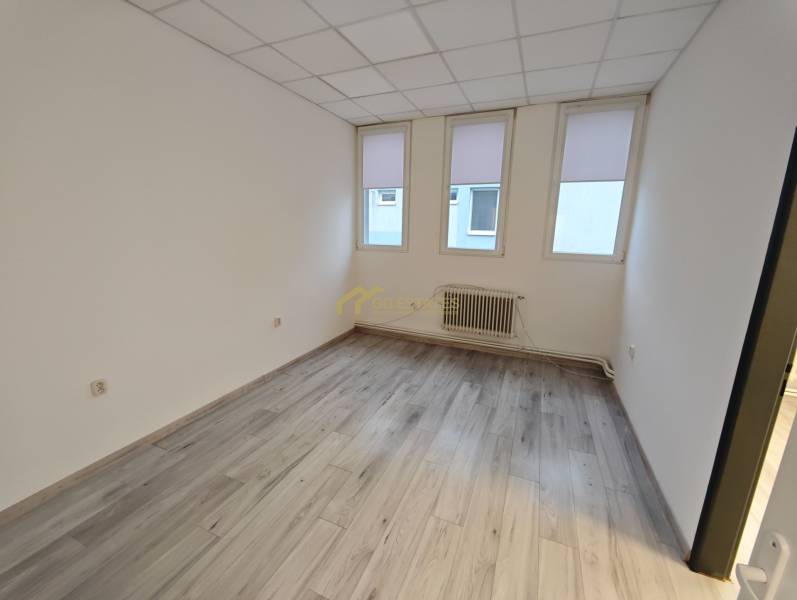 White office with windows, a radiator, and a wooden decor floor.