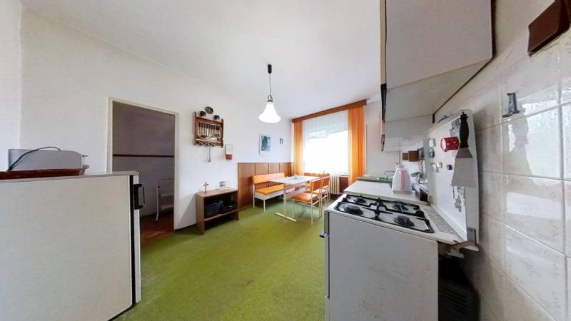 A kitchen in a family house with a gas stove, retro furniture, and a green carpet.