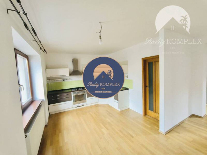 A kitchen in a family house with a wooden decor floor, white cabinets, and green tiles.