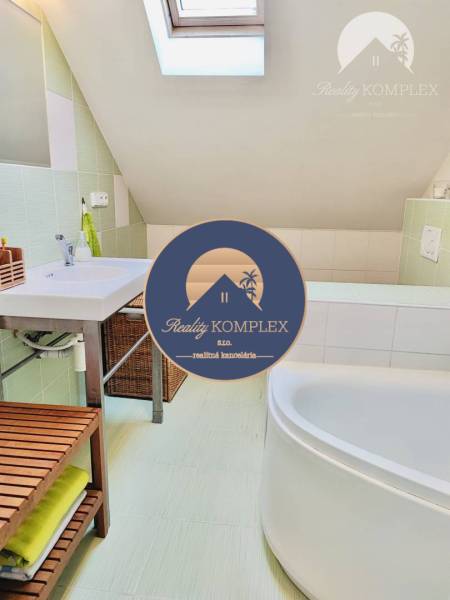 A bathroom in a family house with a bathtub, sink, and skylight.