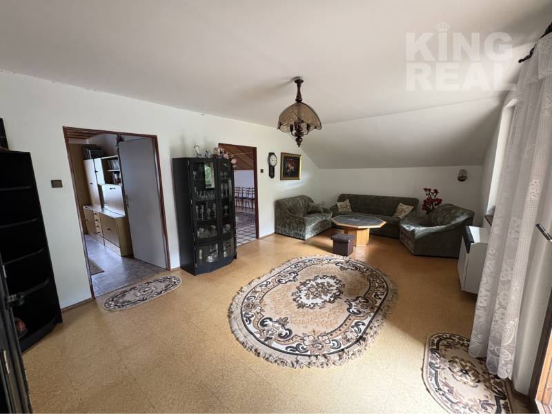 Living room in a family house with carpets, a sofa set, and a display cabinet.