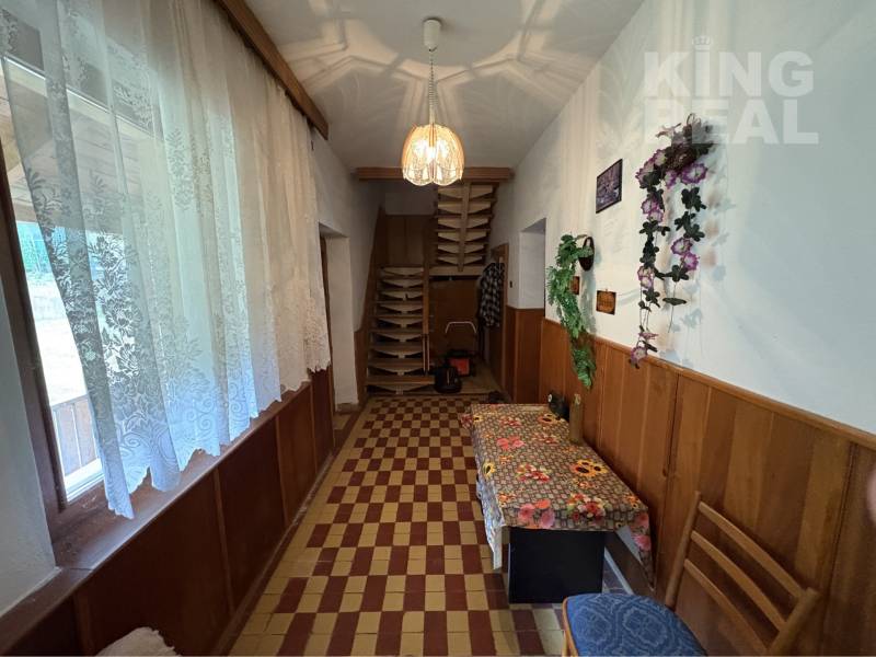 A hallway in a family house with floral decorations, a window curtain, and wooden paneling.