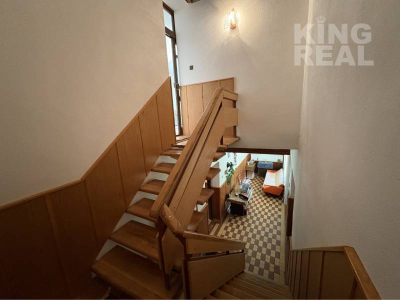 A staircase in a family house with wooden railings leading to the living room.