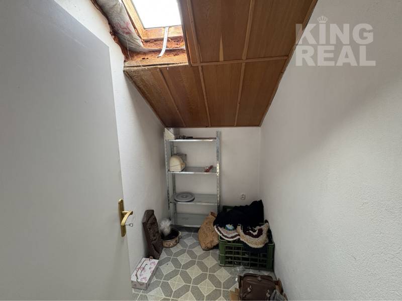 Attic storage room in a family house with a shelf and a skylight.