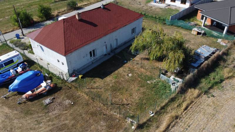 A family house in Zemianska Olča with a red roof, lawn, and boat trailers in the yard.