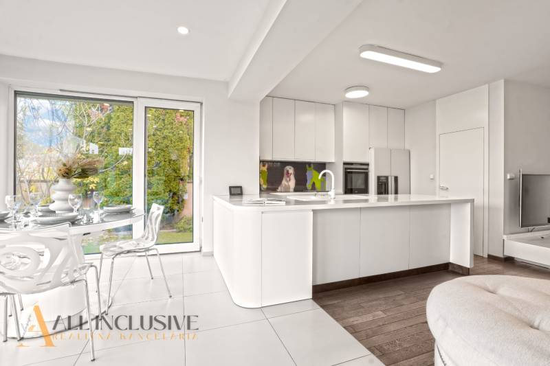 A kitchen in a family house with white cabinets, a wood-patterned floor, and a dining table.