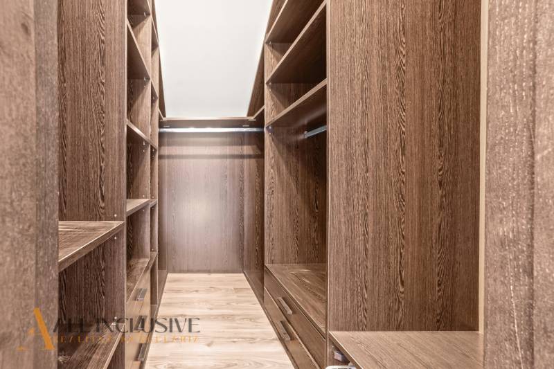 A wardrobe with a wooden decor and storage shelves in a family house.