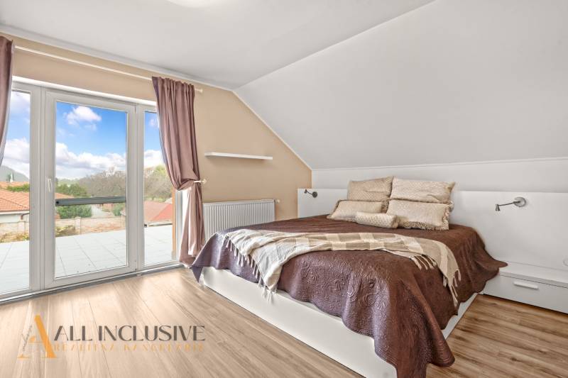 Bedroom in a family house with a balcony, bed, and wooden decor flooring.