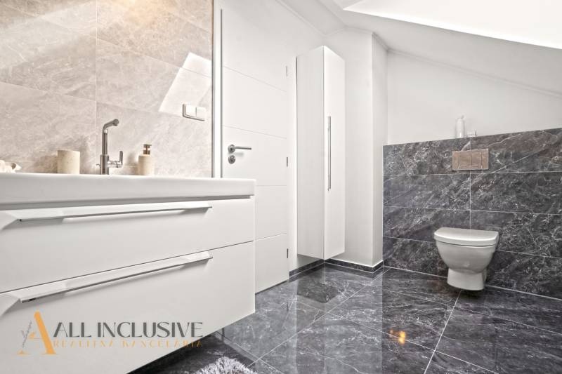 A bathroom in a family house with a toilet, sink, and elegant tiles.