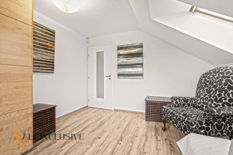 Attic room in a family house with a wooden-patterned floor and a patterned armchair.