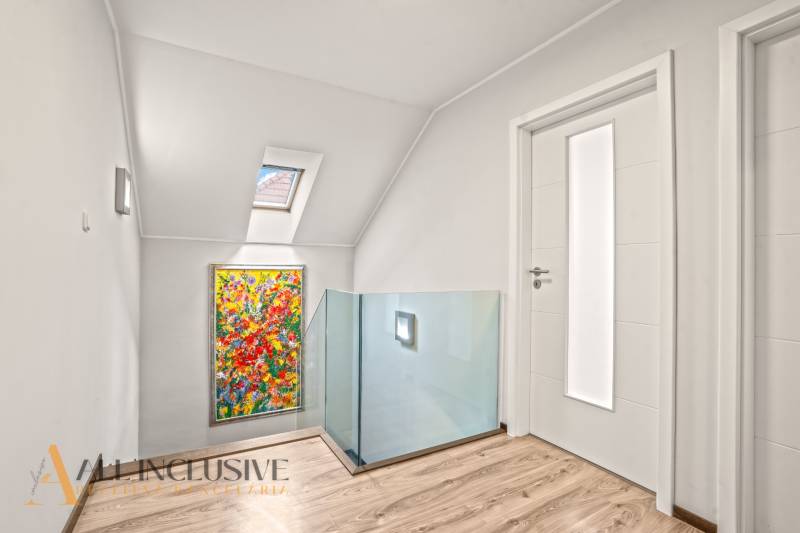 Interior of a family house with a wooden decor floor, colorful painting, and skylight.
