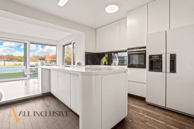 A kitchen in a family house with a wooden decor floor and large windows.