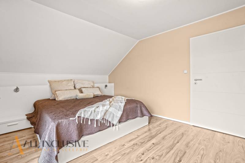 A bedroom in a family house with a wooden decor floor and simple furniture.