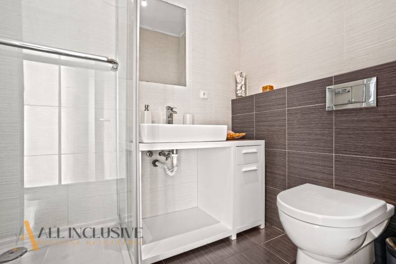 Bathroom in a family house with a sink, shower, and toilet, white tiles.