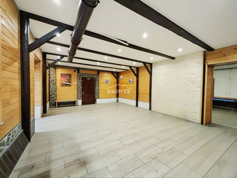 An open room in a family house with wooden decor on the walls and ceiling beams.