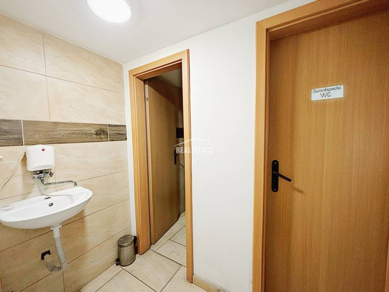Interior of a family house with a toilet and a sink, tiled with light tiles.