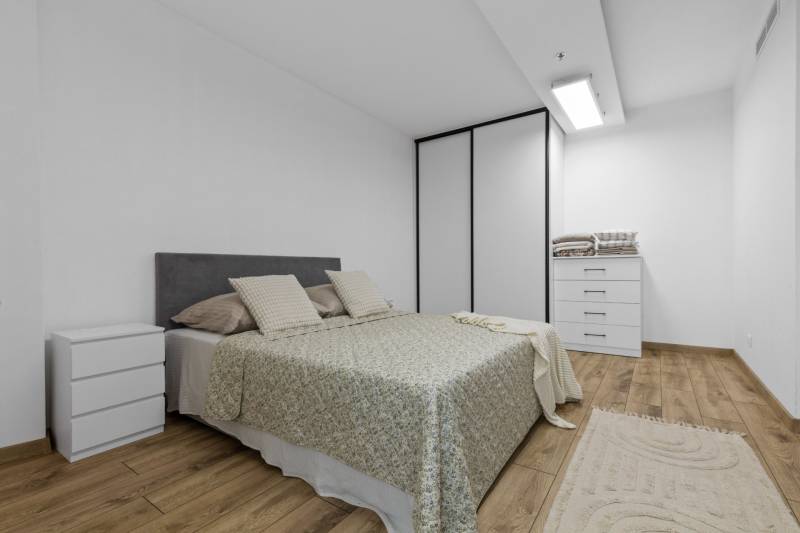 Bright bedroom with a bed, wardrobe, and wooden decor flooring in a 3-room apartment.