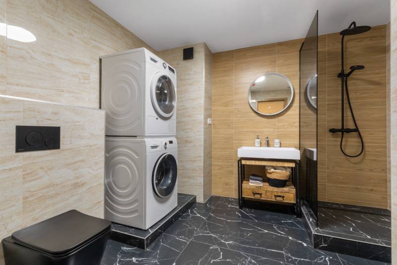 Bathroom in a 3-room apartment with a shower, washing machine, and sink, black tiles.