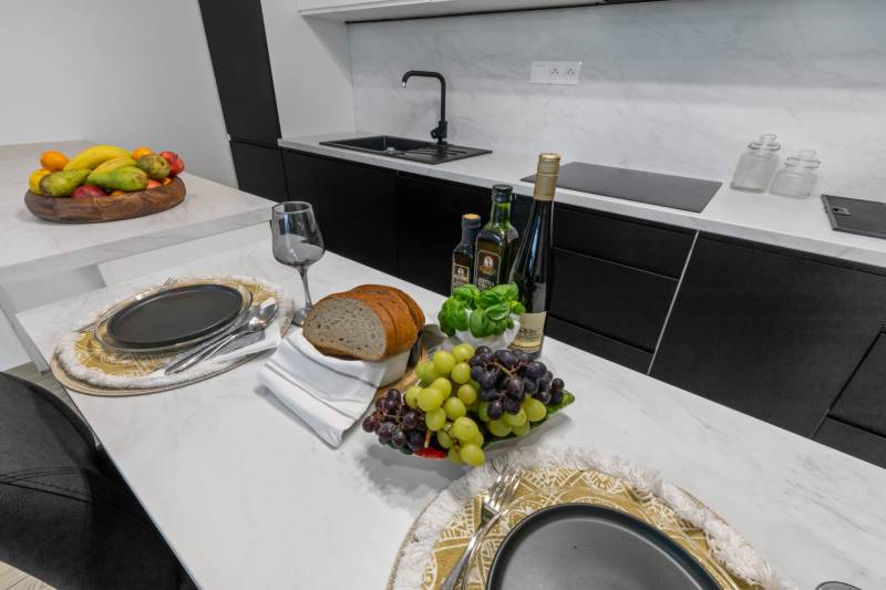 Elegant kitchen in a 3-room apartment with dining, wine, bread, and fruit.