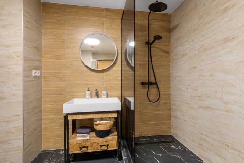 Bathroom with a sink, shower corner, and floor with wooden decor in a 3-room apartment.