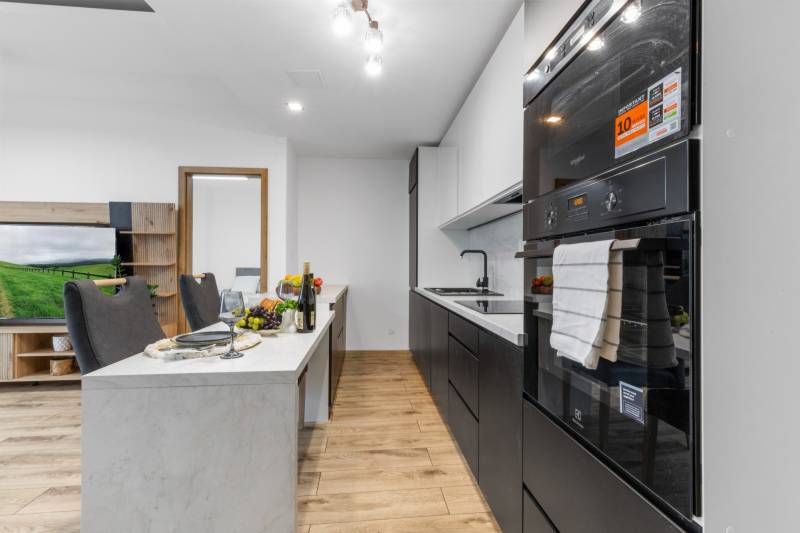 A bright kitchen in a 3-room apartment with a wooden decor floor and modern furnishings.