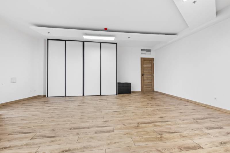 A spacious room with a wooden decor floor, doors, and a built-in wardrobe.