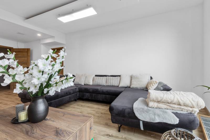 Living room with a dark sofa, white cushions, and a wooden decor floor.