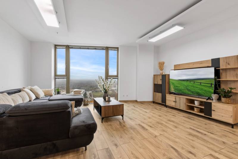 Living room in a 3-room apartment with a sofa, TV wall, and floor with wooden decor.