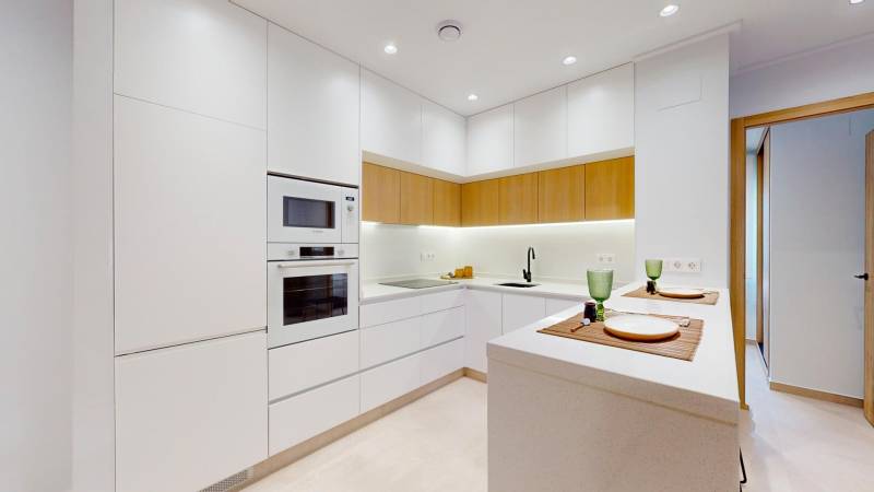 Kitchen area of the Holiday Apartment with white cabinets and integrated appliances.