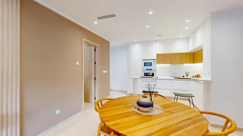 Recreational apartment with a kitchen, wood-patterned flooring, and a dining table.