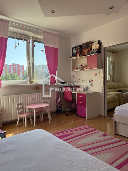 Children's room with pink decor, wooden floor, desk, and sofa.