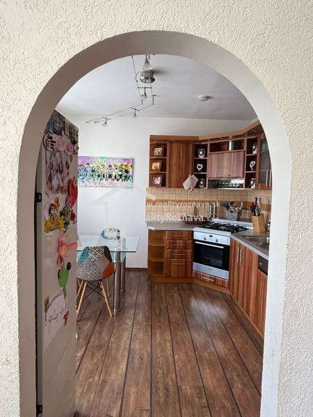 A kitchen in a 3-room apartment with a wooden decor floor and colorful accessories.