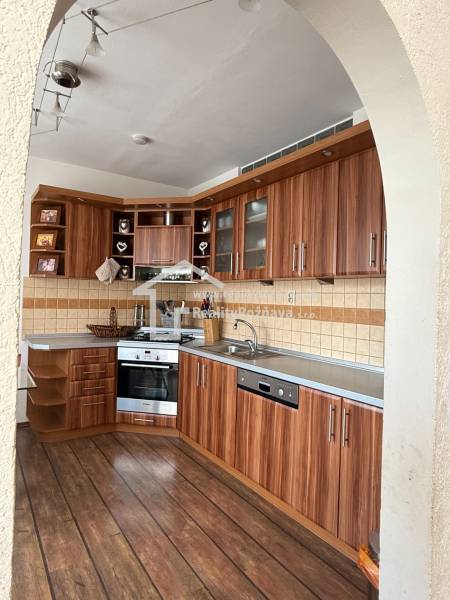 A kitchen in a 3-room apartment with a wooden decor on the floor and built-in appliances.