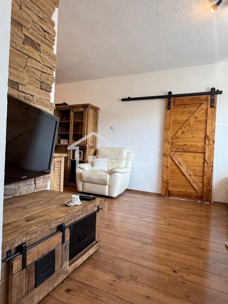 Living room in a three-room apartment with a wood-patterned floor and wooden elements.