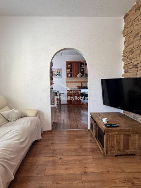 Living room in a three-room apartment with a wooden decor floor and an arched passage.