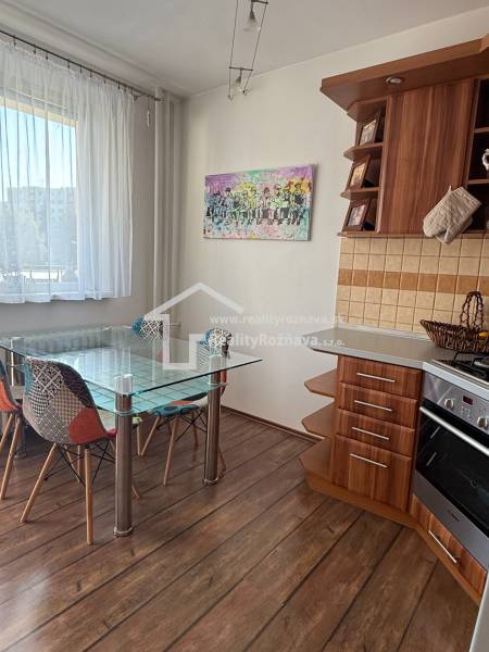 A kitchen in a 3-room apartment with a wooden decor floor and a glass table.