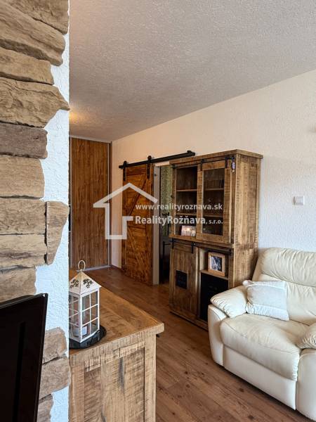 Interior of a 3-room apartment with stone on the wall, a sofa, and furniture with a wooden decor.