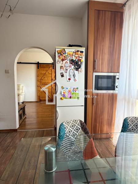 A kitchen in a 3-room apartment with a fridge decor, wooden floor decor, and original chairs.